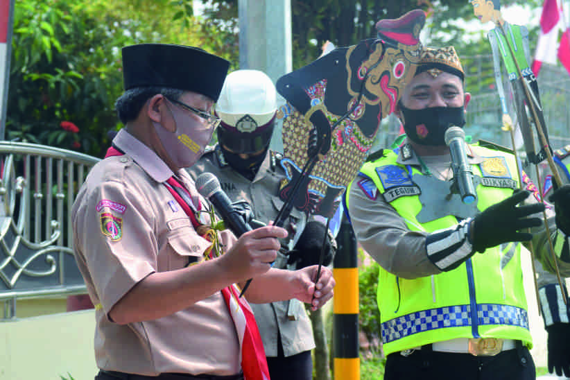 Sekretaris Bidang Pembinaan Anggota Muda (Binamuda) Gerakan Pramuka Kwartir Cabang (Kwarcab) Purbalingga Kak Kusno saat mementaskan wayang bersama dalan dari satlantas Polres Purbalingga, di depan Mapolres Purbalingga (22 Agustus 2020)